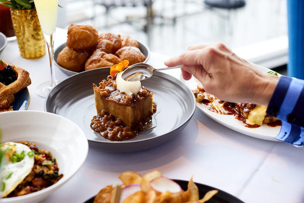 Brunch dishes at Mister A’s in San Diego featuring plated dessert, pastries and savory items in an upscale dining setting.