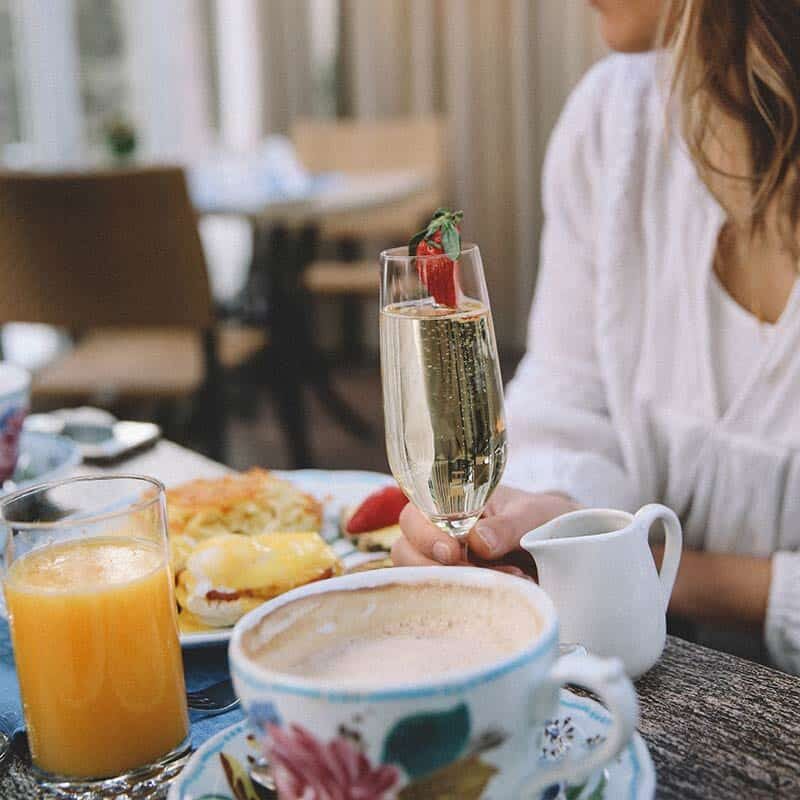 Mother’s Day brunch table with champagne, coffee, orange juice and breakfast dishes in an elegant alpine-inspired dining setting.