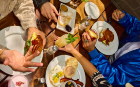 Overhead view of brunch table with eggs, bacon, sandwiches and cocktails at The Windsor.