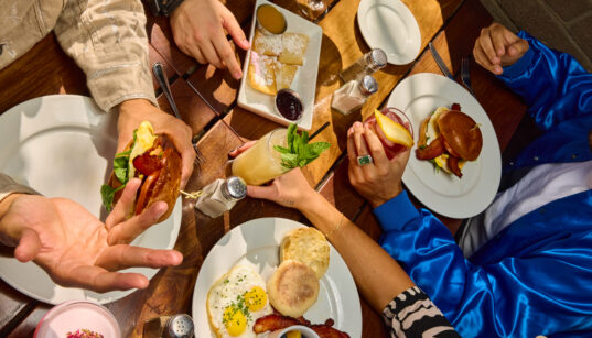 Overhead view of brunch table with eggs, bacon, sandwiches and cocktails at The Windsor.