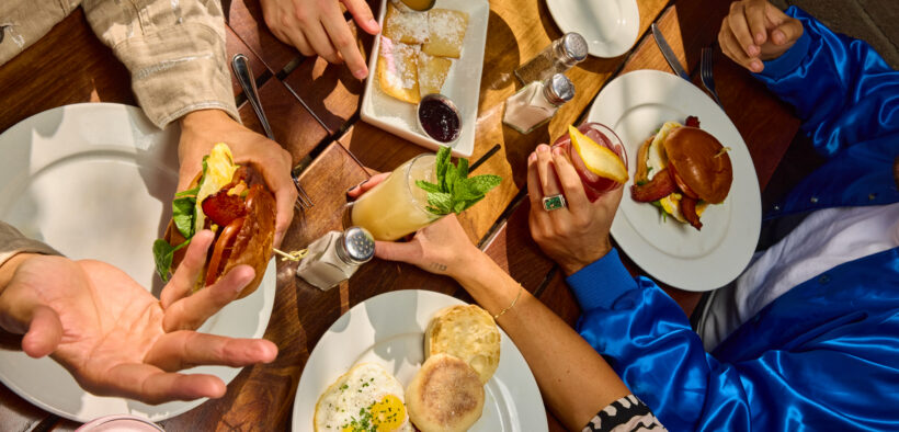Overhead view of brunch table with eggs, bacon, sandwiches and cocktails at The Windsor.