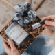 A curated self-care gift box with herbal tea, a satin scrunchie and an essential oil roller, styled in a cozy setting.