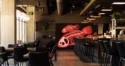Chef preparing sushi at Odd Rabbit in Boulder with neon fish artwork and modern bar seating.