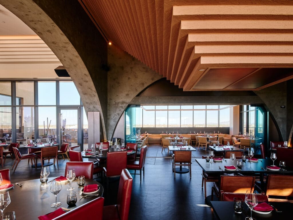 Interior of Prime, A Shula’s Steak House at Wild Horse Pass with modern architecture, red seating and desert views through large windows.