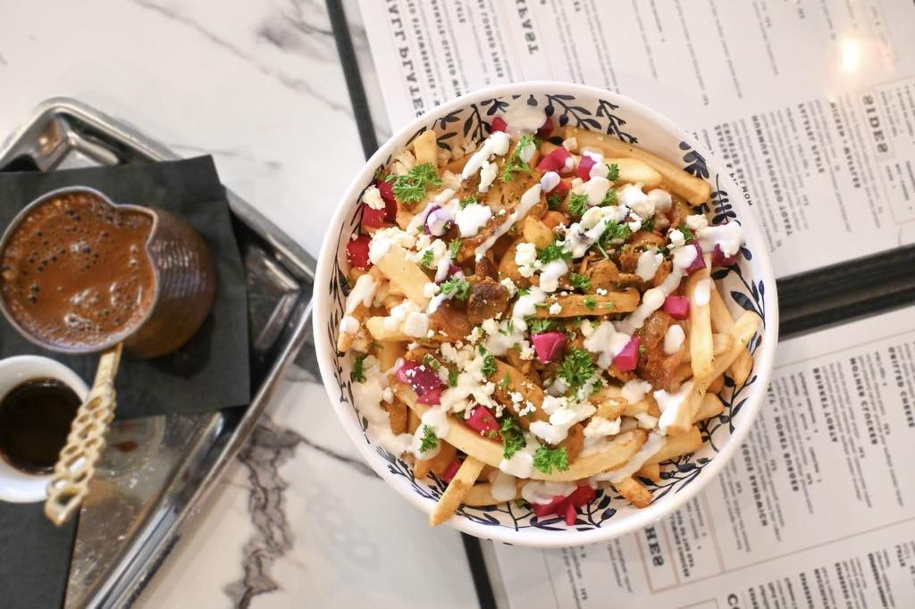 A ceramican filled with salsa next to a Mediterranean bowl with chicken and thick noodles at Salt + Honey in El Paso.