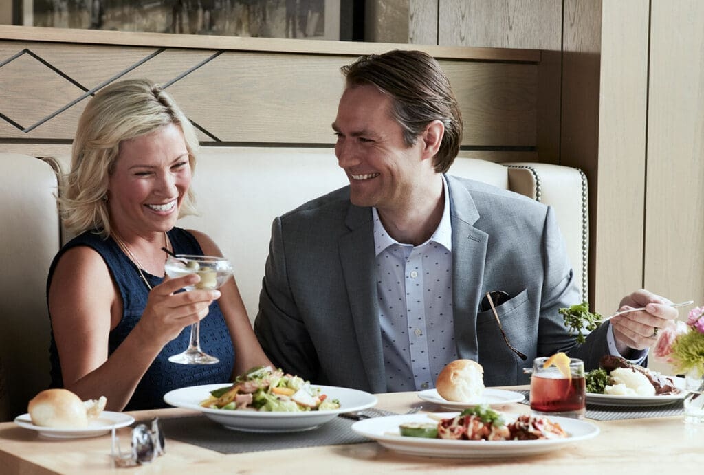 A couple enjoying a Mother’s Day brunch at Silver Pine Restaurant & Bar at Little America Flagstaff, dining on salads and entrées in a bright, comfortable restaurant setting.