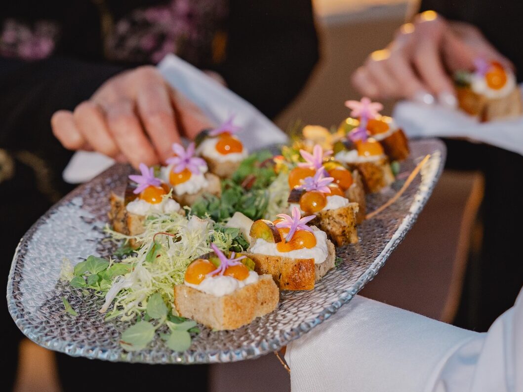 A tray of bruschetta topped with yellow cherry tomatoes, cheese and flowers at Surf and Sand resort.