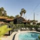 Outdoor pool at Woods Cove Inn in Laguna Beach with palm trees, Spanish-style tile roof and sunny courtyard seating.