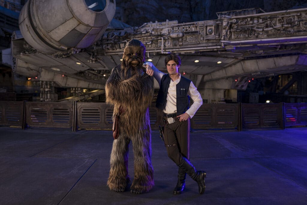 Chewbacca and Han Solo Star Wars characters in front ot the Millennium Falcon at night. 