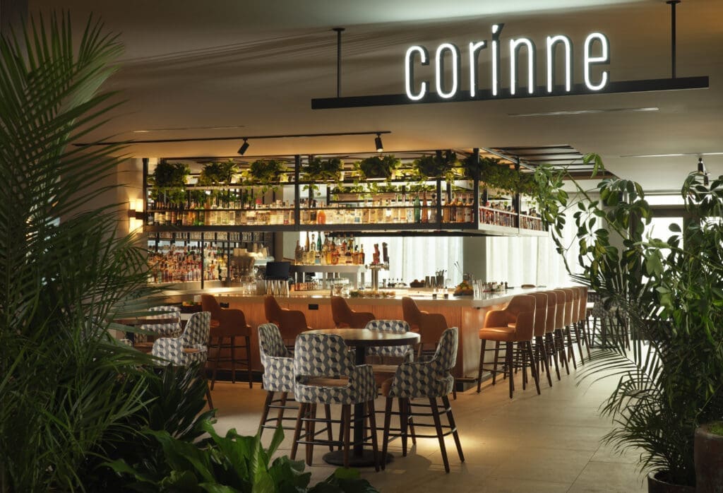 Interior of Corinne restaurant with center bar, seating and plants at Plaza San Antonio Hotel & Spa in San Antonio.