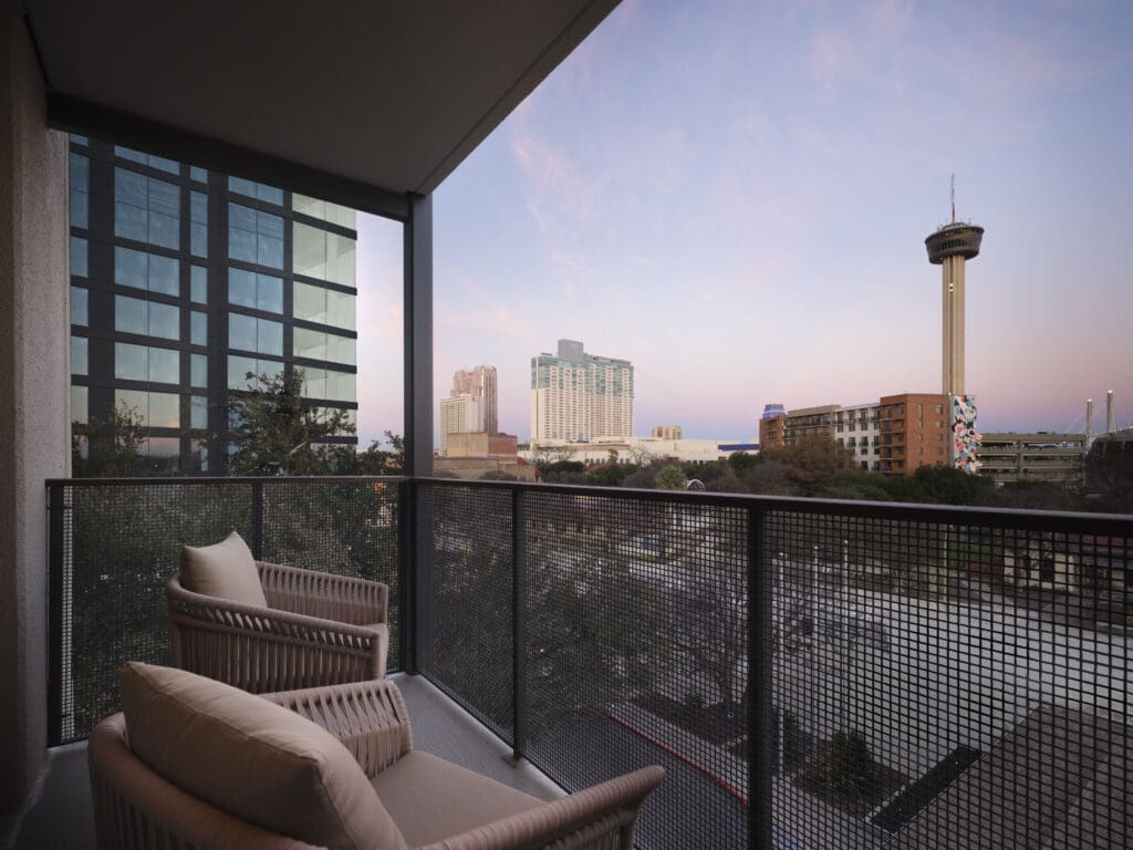 Balcony view with two chairs at the Plaza San Antonio Hotel, overlooking Downtown San Antonio skyline at sunset.