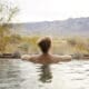 Guest relaxing in an outdoor soaking tub at Miraval Arizona Resort & Spa with desert plants and mountain views in the background.