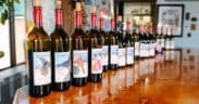 Bottles of Arizona wine lined across a wooden tasting bar inside Chateau Tumbleweed in Clarkdale, Arizona.