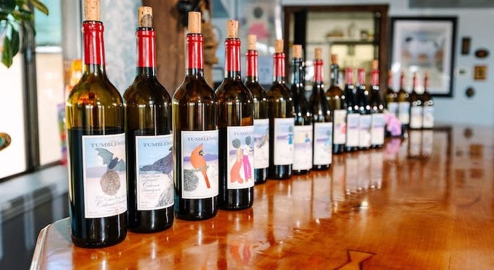 Bottles of Arizona wine lined across a wooden tasting bar inside Chateau Tumbleweed in Clarkdale, Arizona.