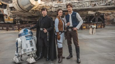 R2D2, Luke Skywalker, Princess Leia, and Han Solo characters stand in front of the Millenieum Falcon at Disneyland Galaxy's Edge.