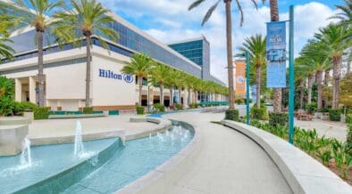 Exterior view of Hilton Anaheim with palm trees, fountain and resort entrance near Disneyland Resort in Anaheim, California.