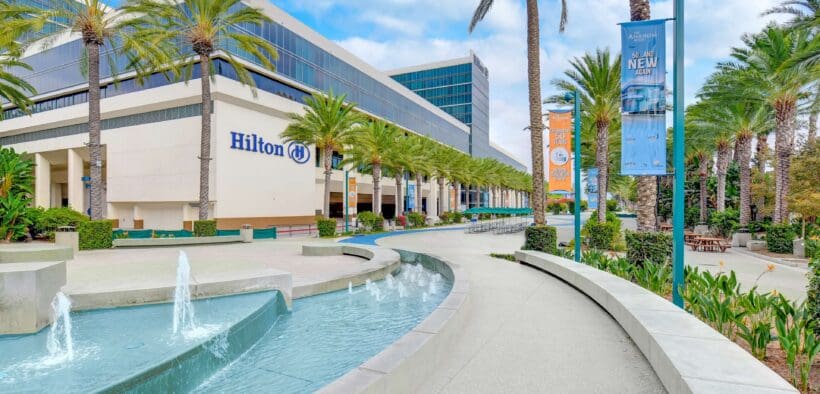 Exterior view of Hilton Anaheim with palm trees, fountain and resort entrance near Disneyland Resort in Anaheim, California.