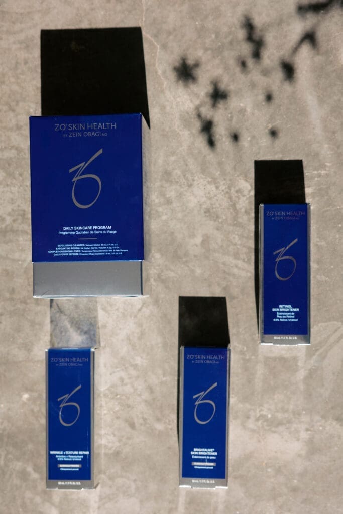A flat lay of professional skincare products arranged on a stone surface, featuring preventative skincare and skin-brightening treatments.