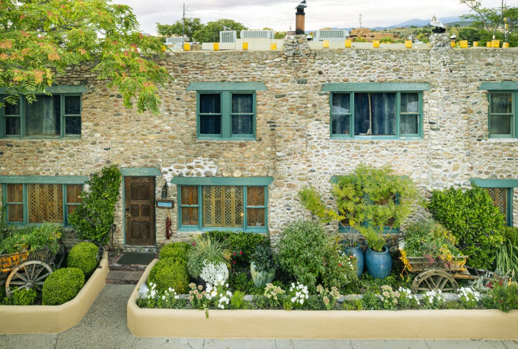 Exterior of The Inn of the Five Graces in Santa Fe, New Mexico featuring stone architecture, lush gardens and Southwestern design details.