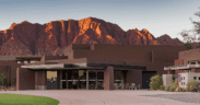 Exterior of the Center for the Arts at Kayenta in Ivins, Utah, with red rock mountains glowing at sunset behind the desert-inspired building.