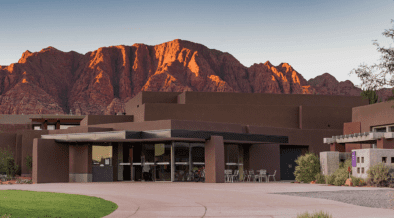 Exterior of the Center for the Arts at Kayenta in Ivins, Utah, with red rock mountains glowing at sunset behind the desert-inspired building.