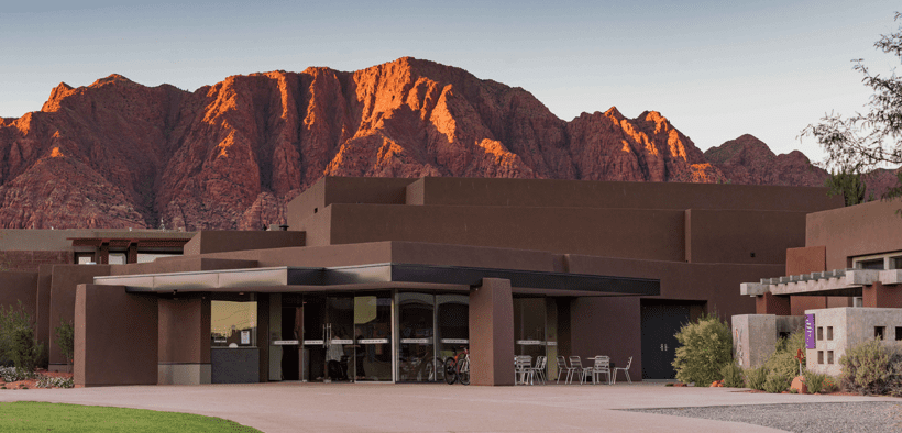 Exterior of the Center for the Arts at Kayenta in Ivins, Utah, with red rock mountains glowing at sunset behind the desert-inspired building.