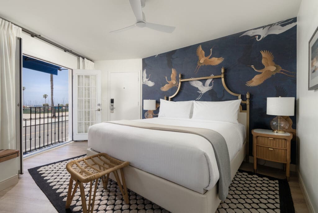Boutique hotel guest room with crane-pattern wallpaper, ocean-view balcony and coastal-inspired décor at Milo Santa Barbara.