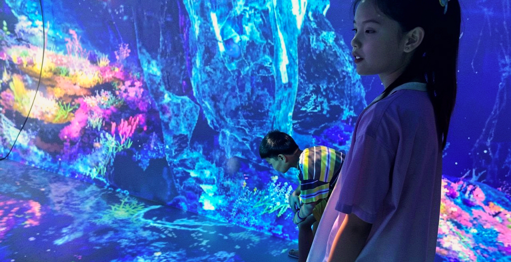 Children exploring a colorful immersive projection environment inside Motion Madness at Immersive Empire.