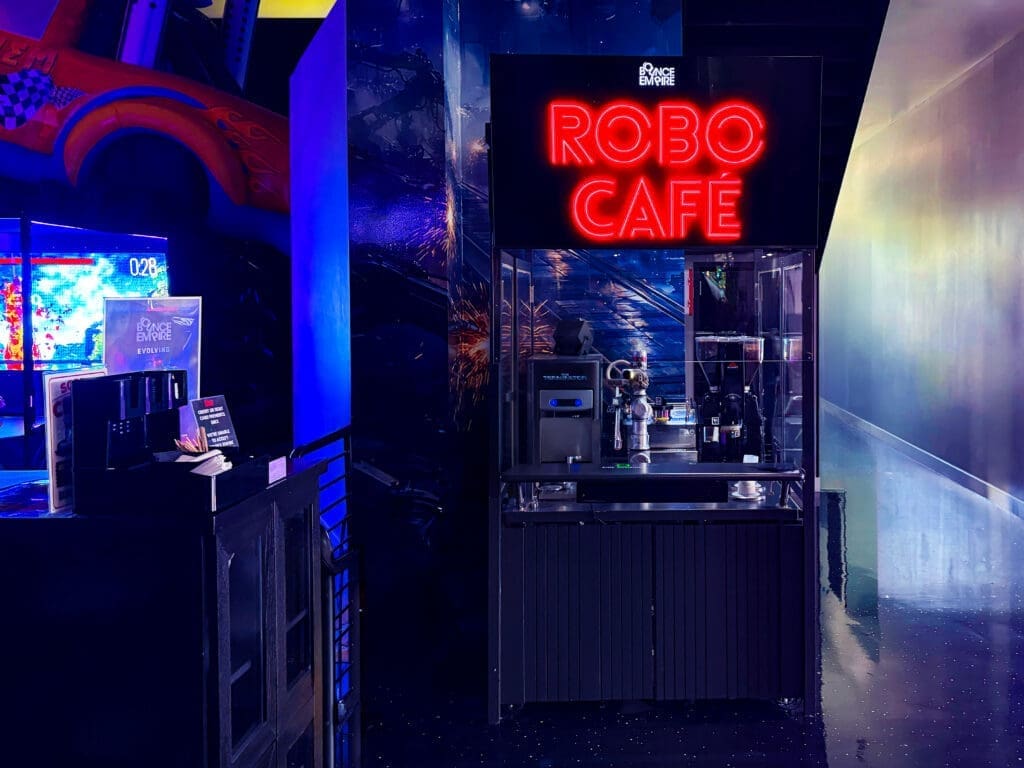 A robotic café station inside Immersive Empire featuring neon lighting and automated beverage service.