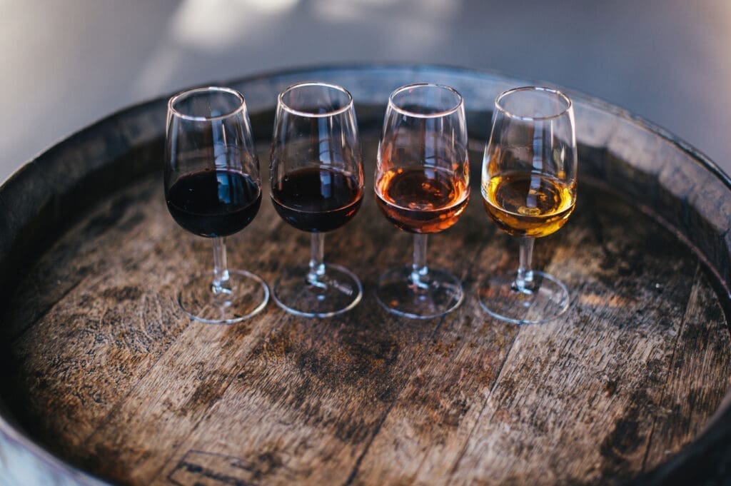 A tasting flight featuring red, rosé and white wines displayed on a rustic wooden barrel table.