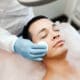 A man receives a professional facial treatment while lying on a spa treatment bed during a skincare appointment.