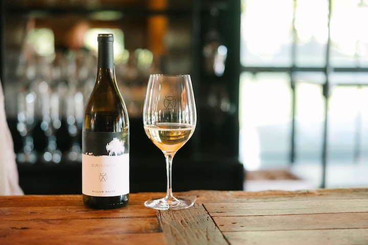 A glass of white wine beside a bottle of D.A.Ranch wine inside the winery tasting room in Arizona’s Verde Valley.