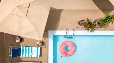 Year-round rooftop swimming pool at Sheraton Denver Downtown with lounge chairs, umbrella seating and a pink flamingo float.