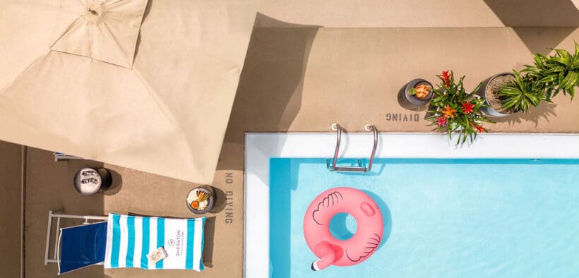 Year-round rooftop swimming pool at Sheraton Denver Downtown with lounge chairs, umbrella seating and a pink flamingo float.