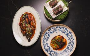 Signature dishes from Pompette and Little Rich Girl displayed on a table, including roasted chicken, Wagyu skewers and a composed entrée in downtown Flagstaff.
