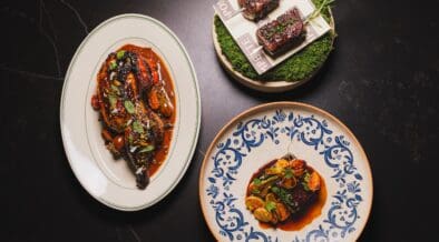 Signature dishes from Pompette and Little Rich Girl displayed on a table, including roasted chicken, Wagyu skewers and a composed entrée in downtown Flagstaff.