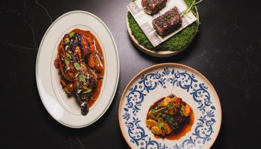 Signature dishes from Pompette and Little Rich Girl displayed on a table, including roasted chicken, Wagyu skewers and a composed entrée in downtown Flagstaff.