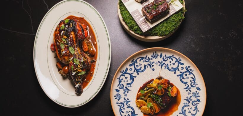 Signature dishes from Pompette and Little Rich Girl displayed on a table, including roasted chicken, Wagyu skewers and a composed entrée in downtown Flagstaff.