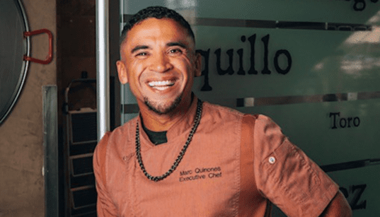 Chef Marc Quiñones smiles while standing inside La Fonda on the Plaza in Santa Fe, New Mexico.