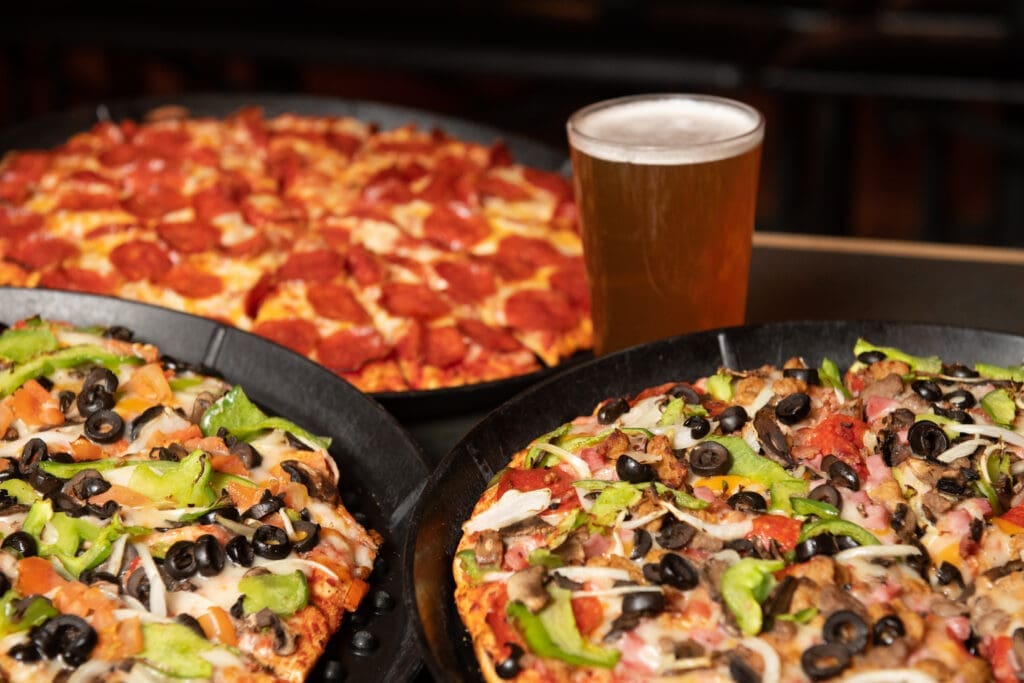Several specialty pizzas and a pint of beer are displayed at Organ Stop Pizza in Mesa, Arizona.