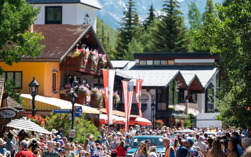 A giant American flag moves through Vail's Fourth of July parade with mountain scenery in the background.