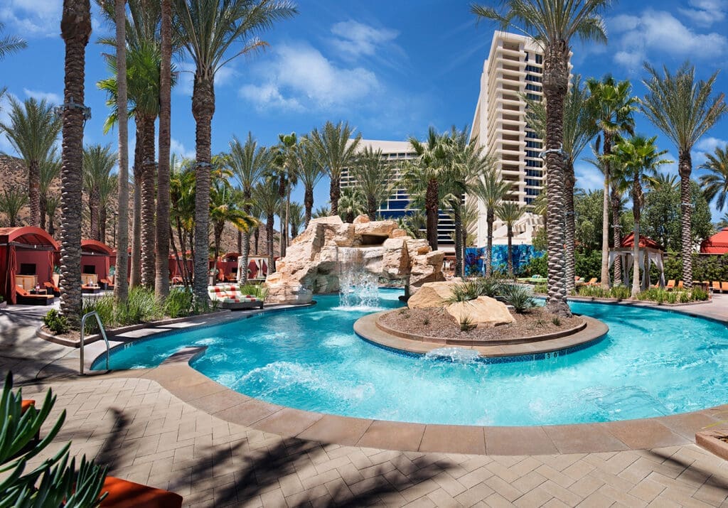Guests float along the lazy river at Harrah's Southern California Resort surrounded by palm trees and cabanas.
