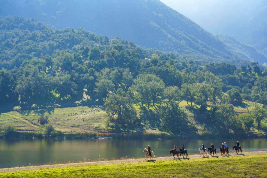 Guests horseback riding beside the lake at Alisal Ranch in Santa Ynez Valley, California.