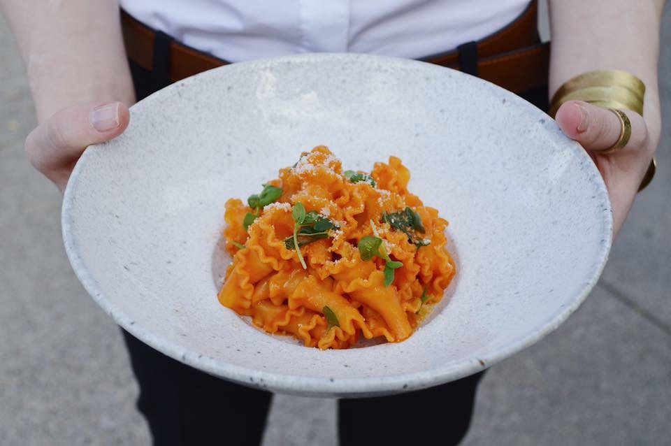 A person holding a plate of pasta from the Fat Ox restaurant in Arizona.