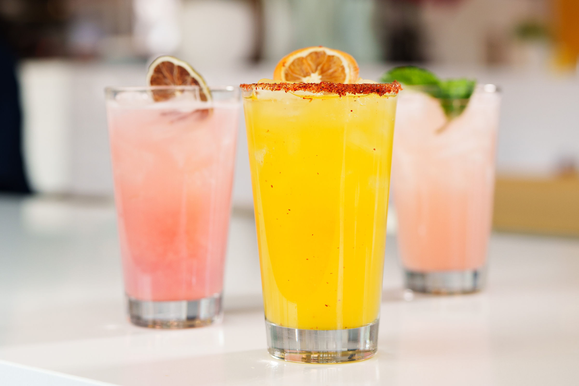 Three summer cocktails with a lighting and a sign that says "Shine On" at Over Easy restaurant.