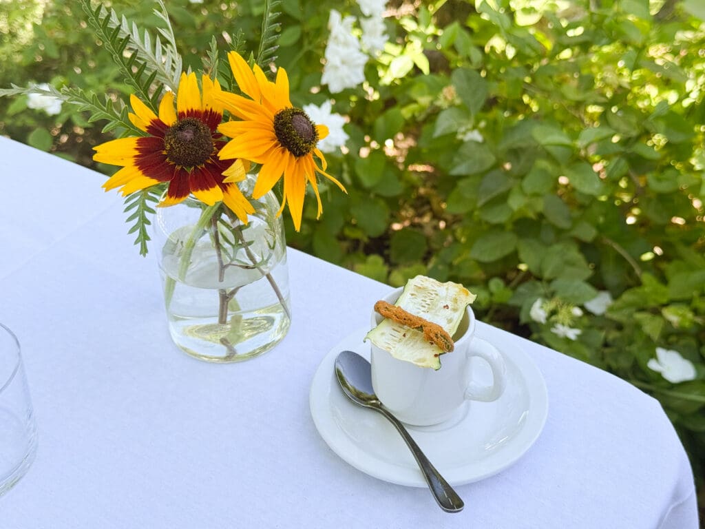 A small vase of sunflowers next to a coffee up and spoon at Quiessence in Phoenix, Arizona