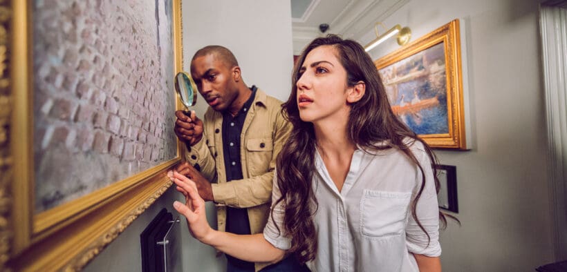 Two guests examine clues inside The Heist escape room at The Escape Game in Gilbert, Arizona.