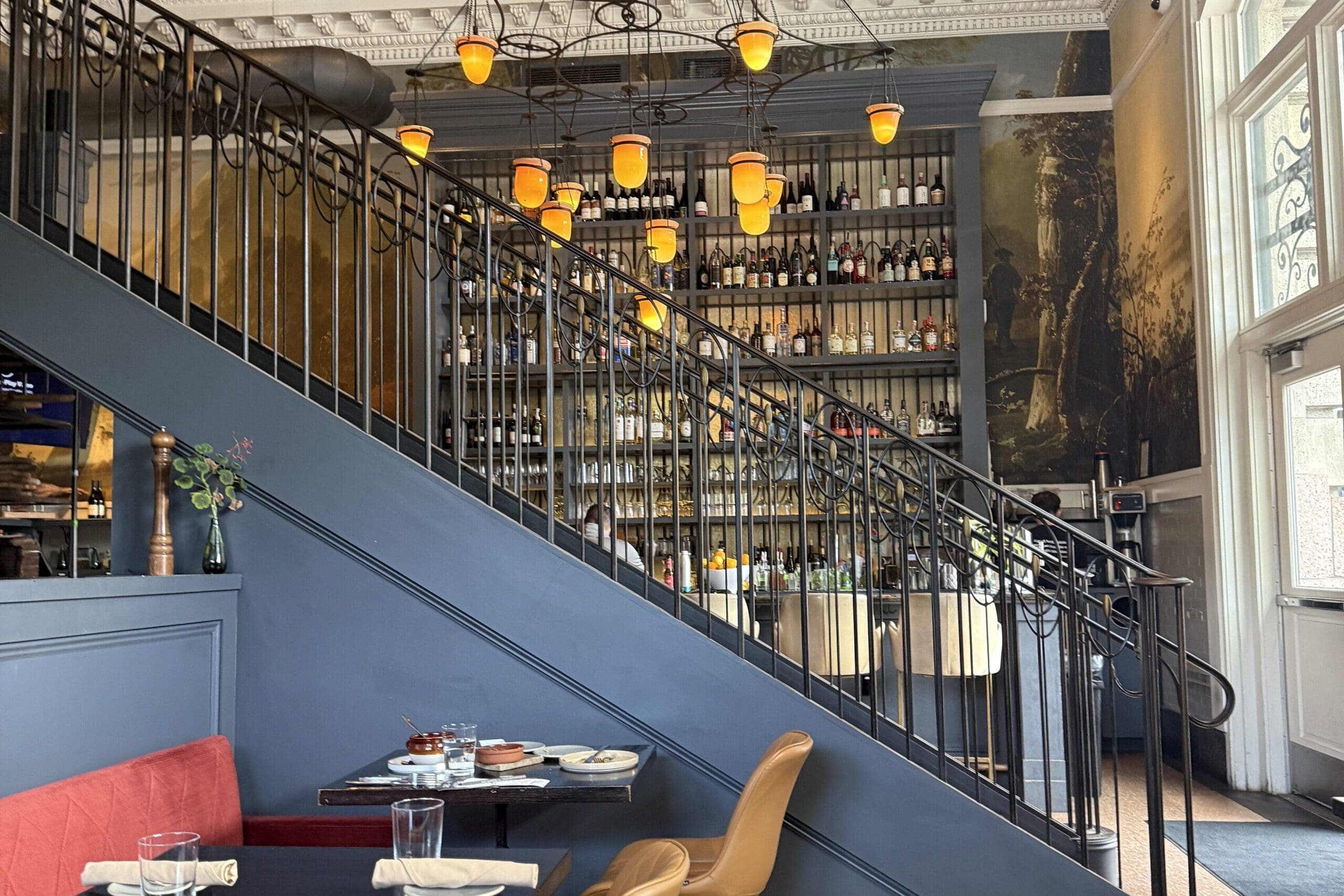 Interior of Ultreia restaurant inside Denver Union Station featuring elegant lighting, a grand staircase and bar seating.