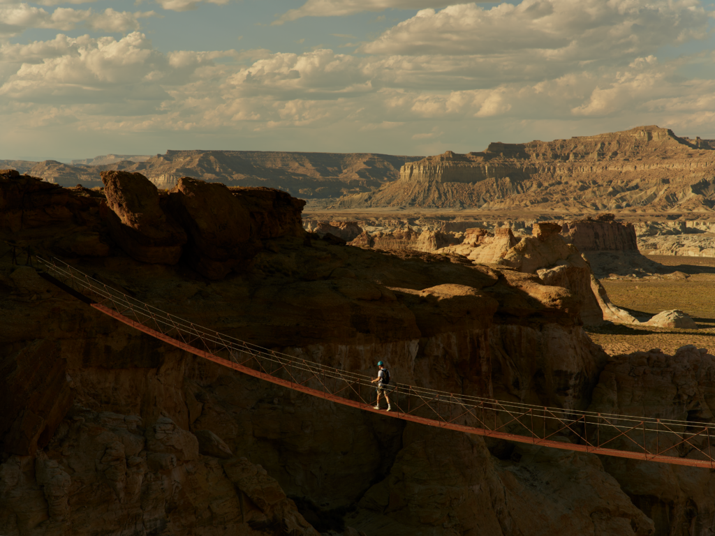 A guest crosses a suspension bridge high above the rocky desert landscape during a via ferrata experience at Amangiri in southern Utah.