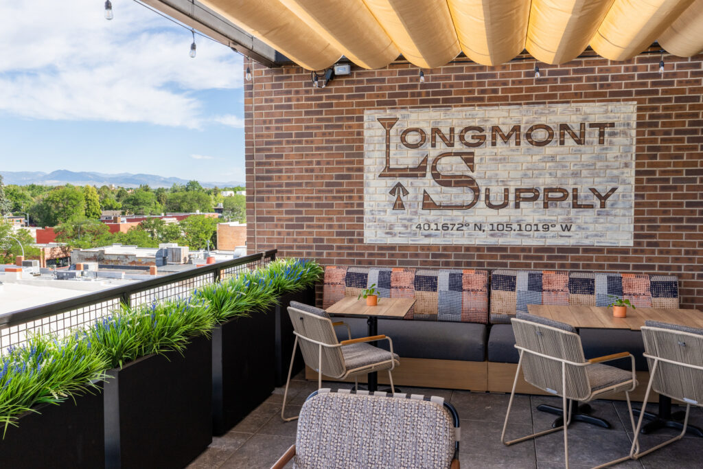 Outdoor seating at Longmont Supply rooftop restaurant overlooking downtown Longmont and the Colorado Front Range.